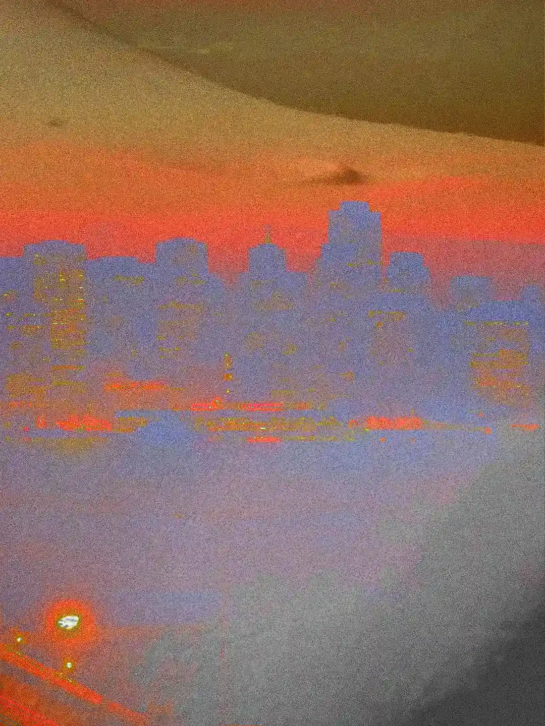 Detail of the artwork Vele dorate: the material silhouette of the city skyline, veiled in blue, emerging from the warm hues of a human abdomen transformed into a landscape